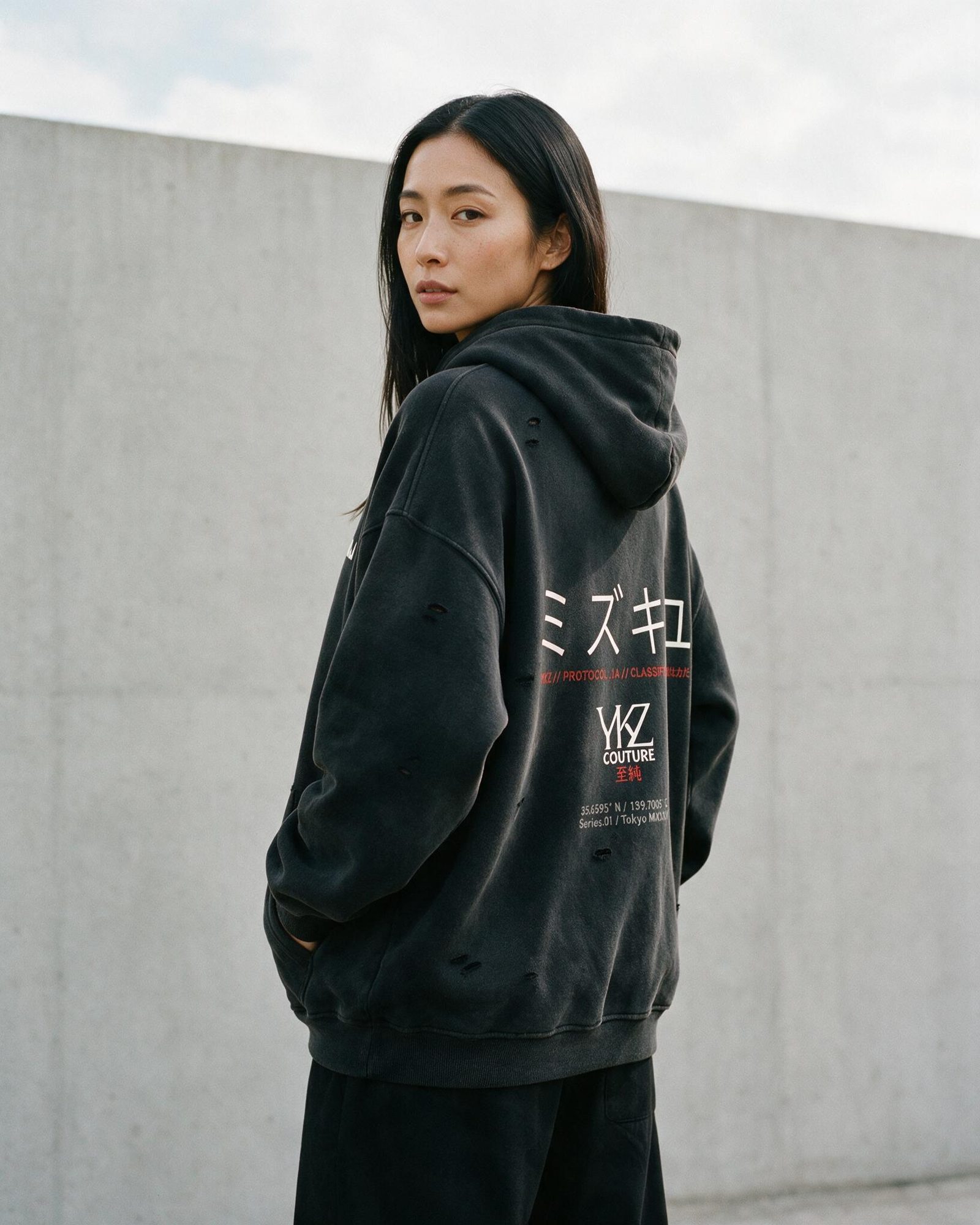 Model wearing a black YUKIZUMI hoodie with a Japanese back print